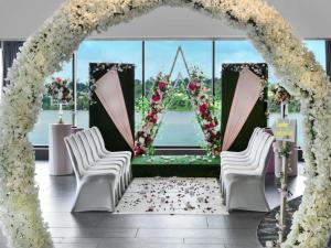 ein Bogen mit weißen Stühlen und Blumen in einem Zimmer in der Unterkunft Pullman Abidjan in Abidjan