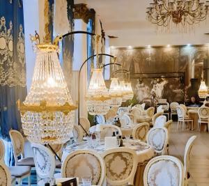 a dining room with chandeliers and white tables and chairs at Hotel Coroana Moldovei in Slănic-Moldova