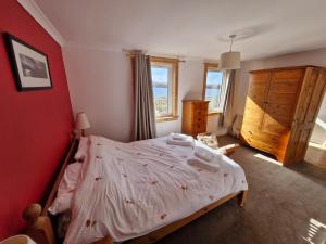 a bedroom with a bed and a red wall at Lochan View Cottage in Breaclete