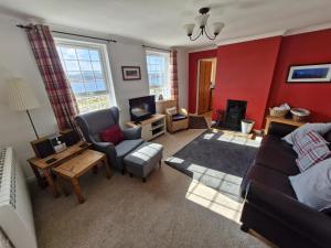 a living room with a couch and a tv at Lochan View Cottage in Breaclete