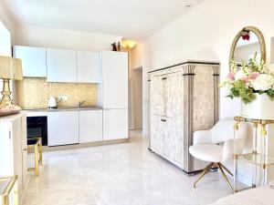 a kitchen with white cabinets and a white chair at Monaco 2bdr luxury apartment, private garden&pool in Beausoleil