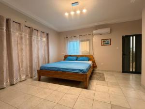 a bedroom with a bed with blue sheets and a window at Villa Lawsmat avec piscine privée et grand jardin in Lomé +27 photos