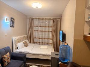 a small living room with a couch and a tv at HIDEOUT BnB with swimming pool in Kiambu