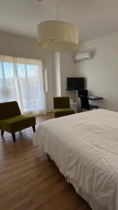 a bedroom with a bed and two chairs and a television at Mercedes Rambla Hotel in Mercedes