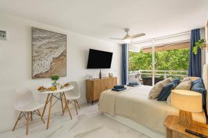 a bedroom with a bed and a table and a tv at Ocean Aura Tenerife in Costa de Adeje