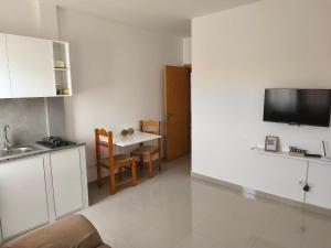a kitchen with a sink and a table with a tv at Ap Doce Lar in Espargos