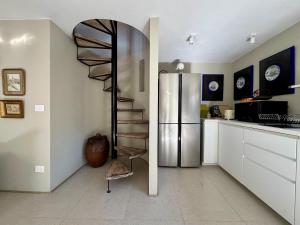 a spiral staircase in a kitchen with a refrigerator at La Casetta in riva al mare in Quercianella +15 photos