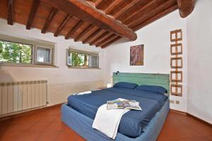a bedroom with a blue bed in a room with windows at Casa Guna - Happy Rentals in Asciano