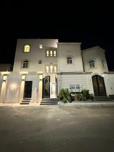 a large white building at night with lights on at شقق الياسمين الفندقية in Medina