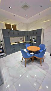 a kitchen with a wooden table and blue chairs at شقق الياسمين الفندقية in Medina