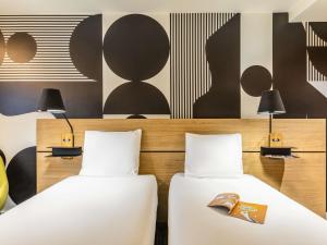 two beds in a hotel room with black and white at Mercure Metz Centre in Metz
