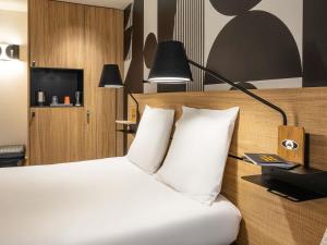 a hotel room with a bed with white pillows at Mercure Metz Centre in Metz
