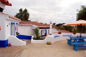 un patio con mesas azules y una sombrilla en Monte das Silveirinhas - Casa Rural, en Silveiras