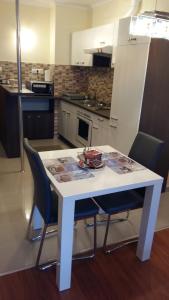 - une cuisine avec une table blanche et des chaises dans l'établissement Isabell Apartments Győr, à Győr