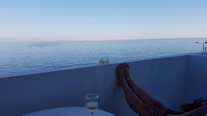 a table with a glass of wine and a view of the ocean at Paralia Hotel & Taverna in Agia Roumeli