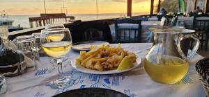 a table with a plate of french fries and a pitcher of wine at Paralia Hotel & Taverna in Agia Roumeli +92 photos