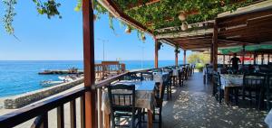 a row of tables and chairs on a balcony overlooking the ocean at Paralia Hotel & Taverna in Agia Roumeli