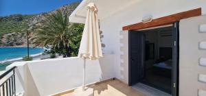 a balcony with an umbrella and a view of the beach at Paralia Hotel & Taverna in Agia Roumeli