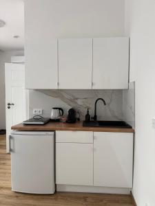 a white kitchen with white cabinets and a sink at Apartamenty Stare Podwórko in Pilica