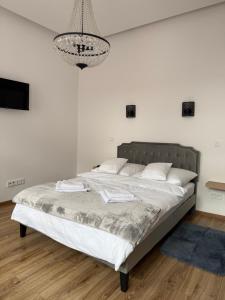 a bed in a white room with a chandelier at Apartamenty Stare Podwórko in Pilica