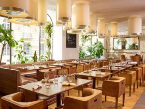 a restaurant with wooden tables and chairs and windows at Sofitel Paris Arc De Triomphe in Paris