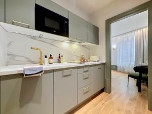 a white kitchen with a sink and a microwave at La suite Capitaine Cook - Centre historique le Puy in Le Puy-en-Velay