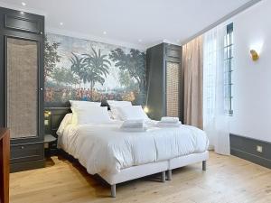 a bedroom with a large bed with a painting on the wall at La suite Capitaine Cook - Centre historique le Puy in Le Puy-en-Velay