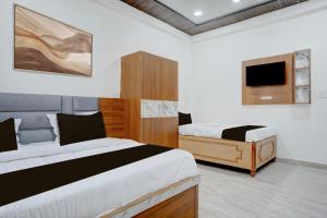 a bedroom with two beds and a flat screen tv at Hotel O Viraj Inn in Gwalior