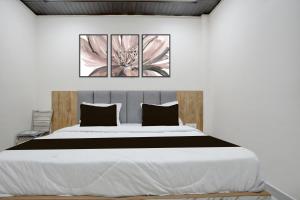 a bedroom with a large bed with three pictures on the wall at Hotel O Viraj Inn in Gwalior