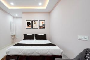 a bedroom with a large white bed with pictures on the wall at HOTEL O KMG GRAND in Bībīnagar