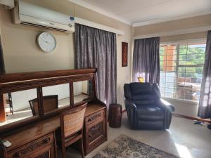 a living room with a chair and a clock on the wall at Pink Pepper Yard in Uniondale