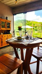 a wooden table in a room with a large window at Villa Pella - Chalé Tulipa- com café manhã in Brumadinho