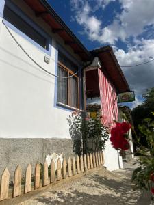 a white house with a fence and a flag at Guest House Brahimasi in Çorovodë