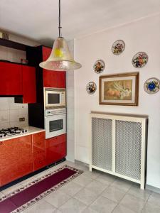 a kitchen with red cabinets and a pendant light at Abir's Apartments 2 in Marghera +62 photos
