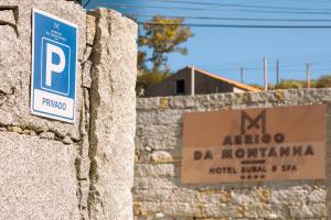 a sign on a stone wall with a parking meter at Abrigo da Montanha Hotel Rural in Sabugueiro