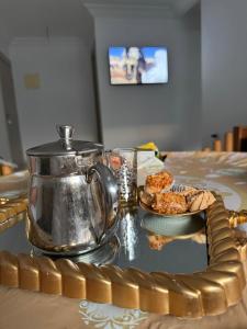 a table with a tea kettle and a plate of food at Apartamento Familiar con Piscina en Bayt Al Bahr Asilah in Asilah