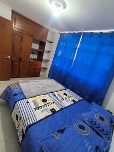 a bedroom with a bed with a blue comforter at Brisas de fusagasuga in Fusagasuga
