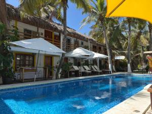 a hotel with a swimming pool with chairs and an umbrella at Hotel Frida Paradise in Brisas de Zicatela