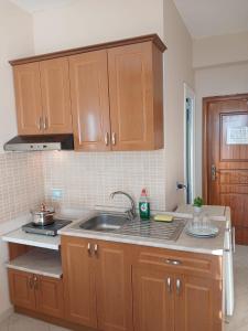 a kitchen with wooden cabinets and a sink at RAHI Rooms in Gjilek +86 photos