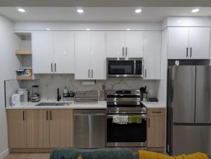 a kitchen with white cabinets and a stainless steel refrigerator at Granny's Hug, a cozy 2 Bedroom Basement Suite in Calgary