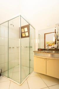 a glass shower with a sink and a mirror at Pousada Vila Taquaras in Balneário Camboriú