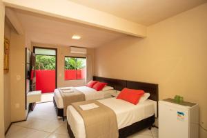 a hotel room with two beds with red pillows at Pousada Vila Taquaras in Balneário Camboriú