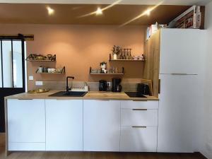 a kitchen with white cabinets and a white refrigerator at Ty Noa - 2-bedroom cottage in Saint-Just +11 photos