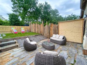 a patio with two couches and chairs and a fence at Ty Noa - 2-bedroom cottage in Saint-Just