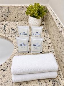 a bathroom counter with three towels and a plant at ＴＨＥ ＯＮＥ Studio! A Vɪʙᴇ Pᴇʀғᴇɪᴛᴀ ɴᴏ Lɪɴs C/Ar Cond in Curitiba