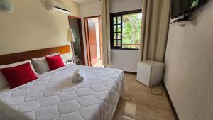 a bedroom with a large white bed with red pillows at Pousada Viking Penedo in Penedo