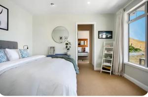a white bedroom with a large bed and a window at Lake Taupo Sunset Lodge in Taupo
