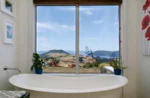 a bath tub in front of a large window at Lake Taupo Sunset Lodge in Taupo