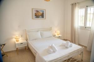 a bedroom with a white bed with towels on it at Blue Water Escape in Agioi Theodoroi