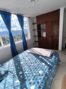 a bedroom with a bed with a blue comforter at Brisas del Santander in Fusagasuga